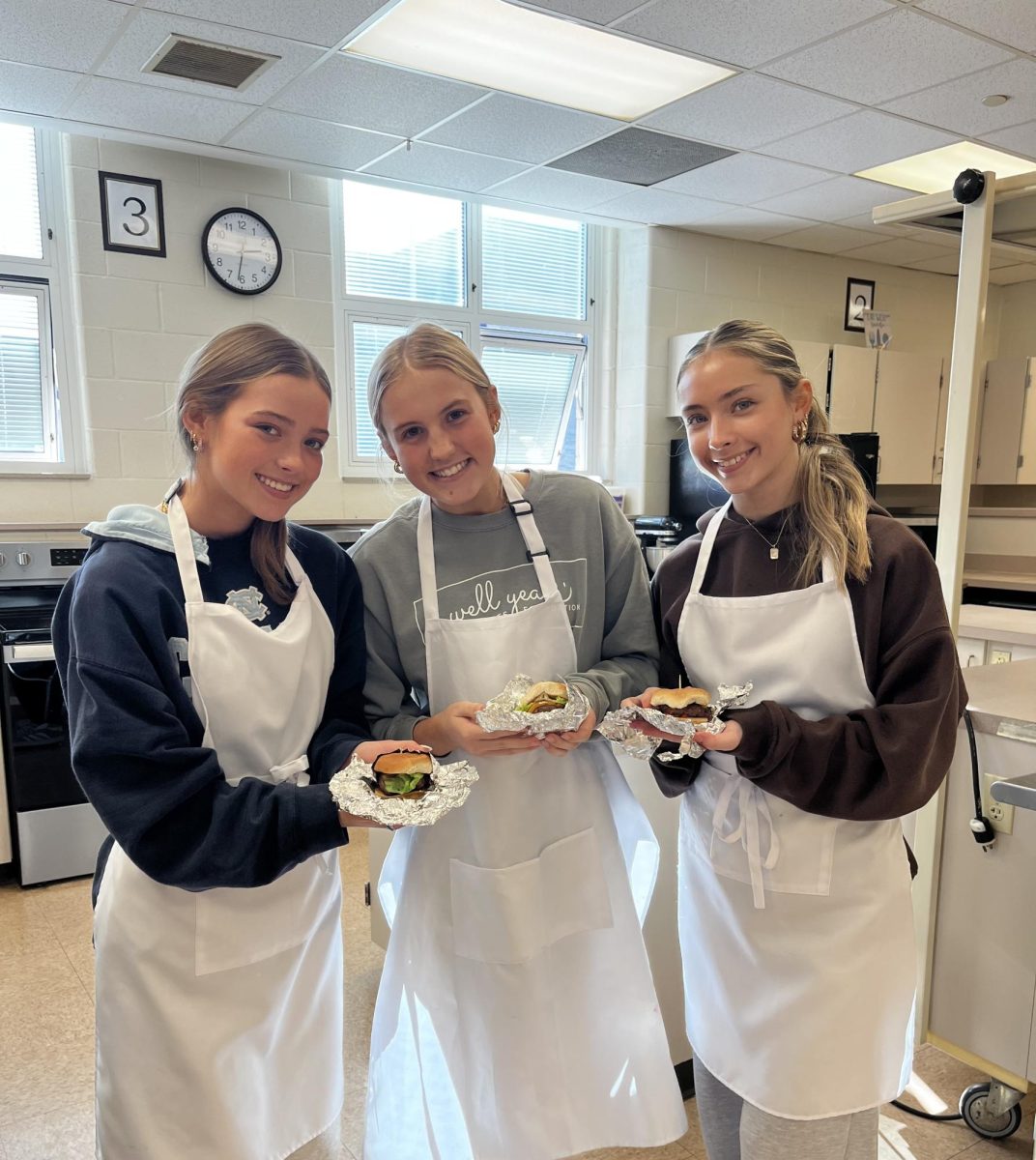 Juniors Eva Hansen, Elise Ryker, and Sydney Vanhentenryck showing off their burger creations in cooking class